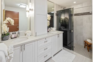 The upstairs guest bathroom boasts elegant tile accents and a spacious walk-in glass shower.