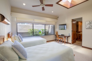 Cozy third bedroom with a lush garden view, natural light, and twin beds for restful nights.