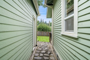 A charming pathway framed by the home’s exterior leads to the peaceful backyard, inviting you to explore and unwind.