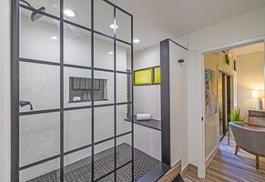 Kapalua Ridge 1421’s spacious walk-in shower boasts black-framed glass, a built-in bench, and elegant tile work.