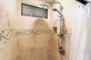Step into your private sanctuary featuring a beautifully tiled shower with dual rainfall and handheld fixtures, plus a built-in niche for your essentials.