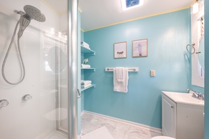 A glass walk-in shower with a rain head, all in cool ocean blue.
