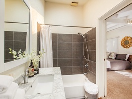 The ensuite bath has shower and tub combo and single vanity, with direct access to the backyard and pool area.