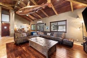 Another angle of the media space with oversized sofa, rich wood finishes, and dramatic island lighting.