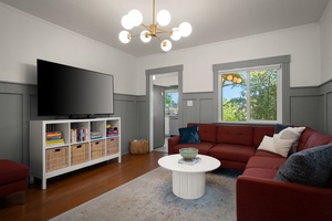 Relax in your bright living room with stylish furnishings, ample storage, and natural light streaming through large windows overlooking lush greenery.
