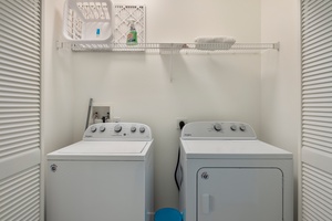 Convenient laundry room with a washer, dryer, and storage shelf.