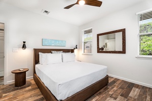 Guest Suite 1 with a plush queen bed, ceiling fan, and bright windows.