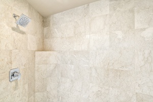Walk-in shower with natural stone tile in the guest bathroom—spacious and sleek.