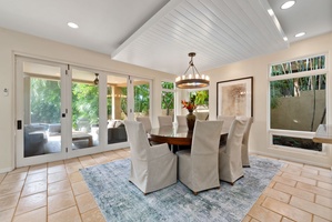 Gather around this elegant dining table where natural light streams through windows overlooking lush tropical gardens, creating the perfect setting for memorable meals.