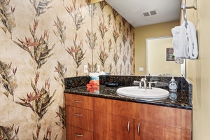 Powder room with vibrant tropical wallpaper and a polished granite vanity.