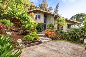 Charming garden entrance framed by vibrant tropical plants and mature landscaping.