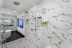 Polished stone tiles and dual shower heads enhance the spa-like experience.