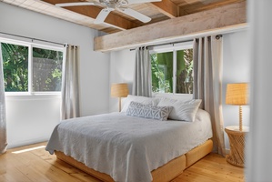 Drift off comfortably in the serene bedroom framed by tropical greenery outside.