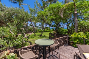 Private beachfront lanai framed by lush tropical gardens offers breathtaking sea views and peaceful outdoor dining beneath swaying palms.
