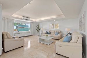 Beneath vaulted ceilings, the main living area is anchored by clean lines, soft tones, and panoramic views of the ocean horizon.