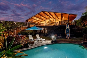 Stunning architectural design, featuring a crystal-clear pool surrounded by lush gardens under dramatic evening skies.