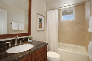 Upstairs full bathroom a bathtub, dark granite countertop and wood cabinetry.