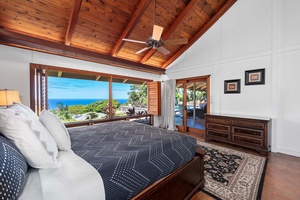 Tranquil primary bedroom with large windows, private lanai access and tropical views.