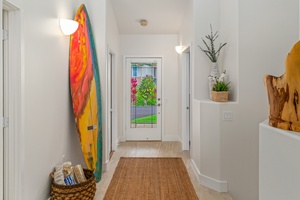 Entry hallway with surf art and tropical views sets a relaxed island tone.