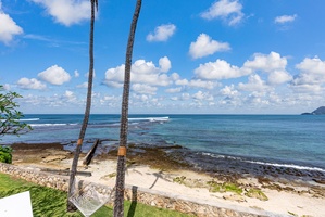 Tropical oceanfront setting with swaying palms, pristine beach access, and endless blue horizon stretching beyond your private coastal retreat.