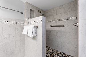 Spacious walk-in shower with pebbled flooring for added comfort.