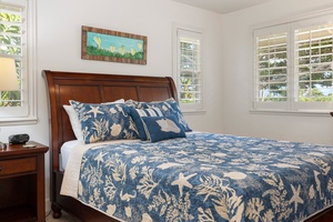 Drift off in your coastal-themed bedroom featuring ocean-blue linens and warm wood furnishings, with natural light streaming through plantation shutters.