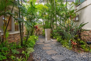 Stone pathways and vibrant palms create a serene garden setting tucked within the property grounds.