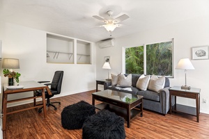 Relax in your stylish office space with cozy sleeper sofa, workspace, and tropical garden views through large windows.