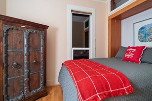 Second guest bedroom featuring warm tones, holiday pillows, and a red throw for a festive touch.