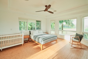Wake up to tropical views through floor-to-ceiling windows in this bright bedroom, complete with a cozy crib for your little one.