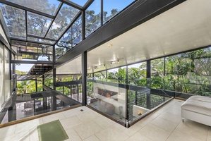 Sunlit atrium with glass walls and skylights, bringing the tropical outdoors inside.