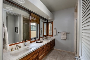 Guest bathroom with dual sinks, a large mirror, and natural light, offering a comfortable and functional space.