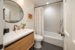 This hallway bathroom features a deep soaking tub, Hawaiian-inspired touches, and soft natural lighting for added calm.