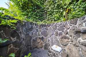 Refreshing outdoor shower surrounded by lava rock and tropical greenery—perfect post-beach rinse.