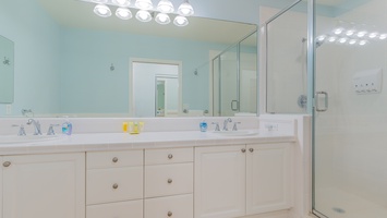 The primary guest bathroom with a shower and ample lighting.