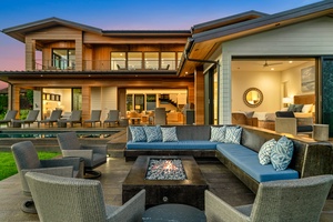 Modern luxury property featuring expansive outdoor living spaces with fire pit seating and seamless indoor-outdoor flow at twilight.