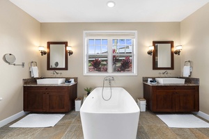 Luxurious primary bathroom showcases a deep soaking tub and granite-accented split vanities.