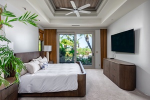 Spacious bedroom with a ceiling fan, modern furnishings, and large windows that open to a tropical view.