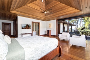 Relax in your spacious guest suite with soaring wood ceilings, where white armchairs invite morning coffee while tropical gardens beckon just outside.