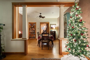 Open dining room with a glowing Christmas tree, offering a festive setting for holiday feasts.