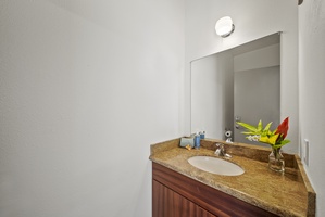 Simple half bath with wood cabinetry and natural stone counter—perfect for guest convenience.