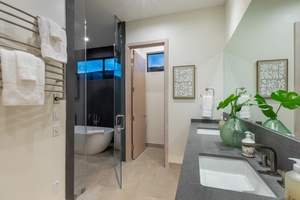 This modern bathroom marries functionality with sleek design, featuring a spacious walk-in shower and a refined, dual-sink vanity.