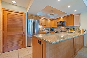 The modern kitchen at Kahana Sunset B4B boasts granite countertops, stainless steel appliances, and ample storage for easy meal prep.