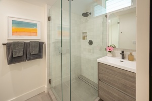 Ensuite bathroom with a glass walk-in shower and contemporary vanity provides private luxury for your guests.