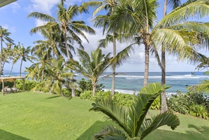 Serene garden area with tall palm trees and a view of the sparkling blue sea.