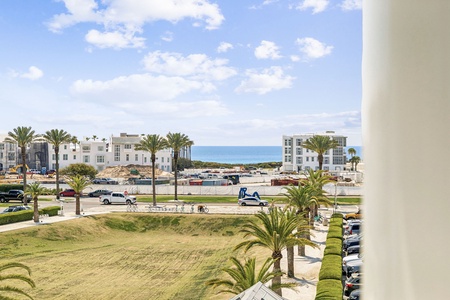 Coastal view showcasing the Mediterranean seaside town with palm-lined streets and white buildings leading to the sparkling blue sea.