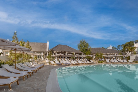 Crystal-clear pool surrounded by luxury loungers under umbrellas, perfect for your afternoon relaxation.