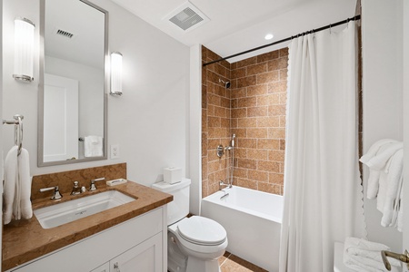 Step into your modern bathroom featuring warm stone tiles and fresh linens awaiting your arrival.