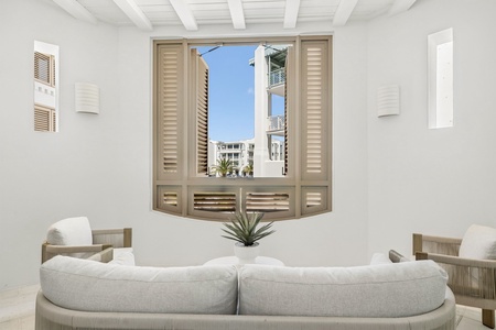 Relax in this serene living room featuring elegant coastal design, plush seating, and shuttered windows framing views of the surrounding architecture.