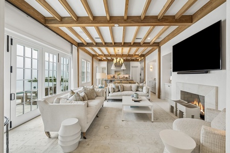 Settle into this sun-drenched living space featuring exposed beam ceilings, plush seating around a modern fireplace, and an open flow to your private kitchen and dining areas.